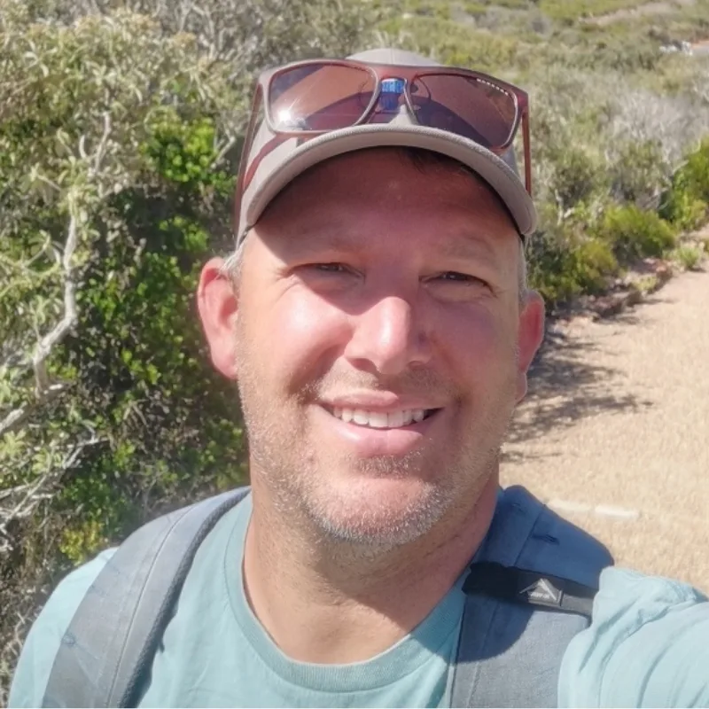 Mark Ascott-Evans hiking through coastal vegetation in South Africa